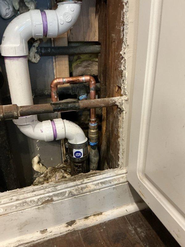 Replaced corroded copper U-bend piping assembly and installed new PVC drain components in utility area. Addressed moisture damage to surrounding wooden structural elements. Documented pre/post repair conditions with photos showing successful transition from deteriorated copper plumbing to properly sealed PVC system with appropriate joint connections.