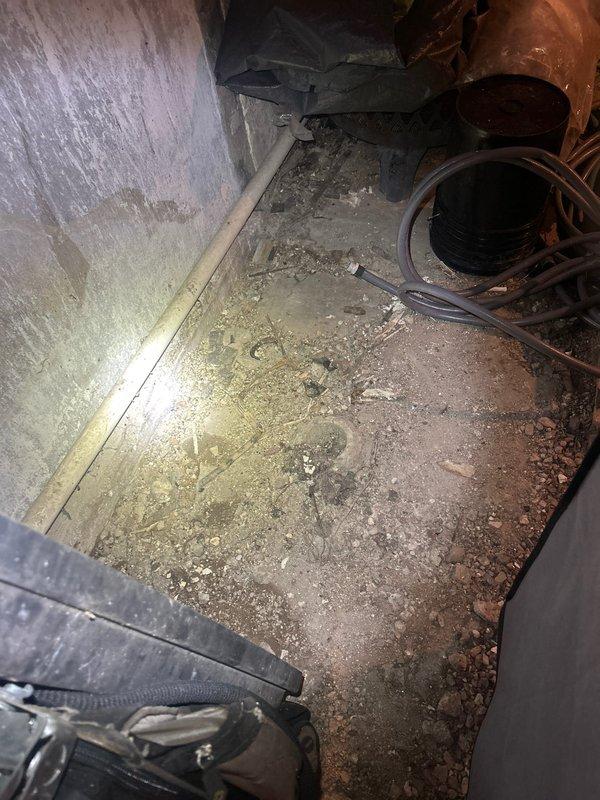 Conducted inspection of residential drainage system, identifying significant copper pipe corrosion and mineral buildup in utility area. Observed compromised pipe integrity with greenish-blue patina formation and deterioration at connection points. Basement area shows evidence of moisture issues with debris accumulation and potential water damage to surrounding concrete surfaces.
