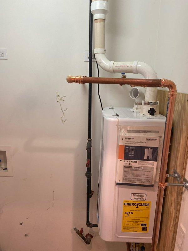 Completed installation of a new tankless water heater mounted on plywood backing with proper copper supply lines and PVC venting system. Installed shutoff valves, connected all necessary plumbing components, and verified proper operation of the unit's digital control system. Left installation area clean with manufacturer documentation attached to unit for customer reference.
