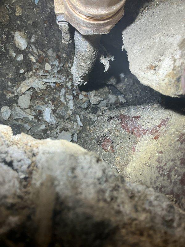 Responded to callback for bathroom plumbing issues. Upon inspection, found significant wall damage with exposed framing and deteriorated drain pipe assembly. Documented severe corrosion on brass valve and metal piping with visible deterioration in the underground access area. Took detailed photos of damage for further assessment.