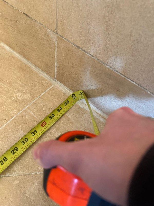 Conducted on-site measurements of tiled wall-floor junctions in preparation for providing estimates for additional plumbing work. Measurements were taken at multiple corner areas, with particular attention to the 27-35 inch sections where potential installation or repairs may be needed.