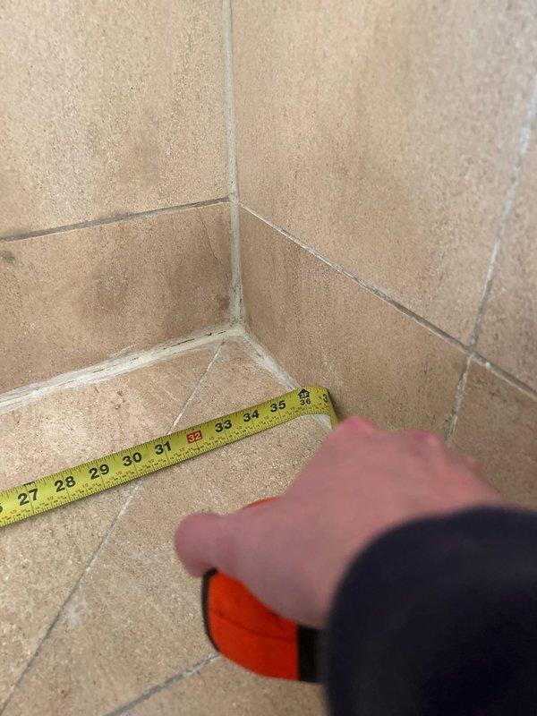 Conducted on-site measurements of tiled wall-floor junctions in preparation for providing estimates for additional plumbing work. Measurements were taken at multiple corner areas, with particular attention to the 27-35 inch sections where potential installation or repairs may be needed.