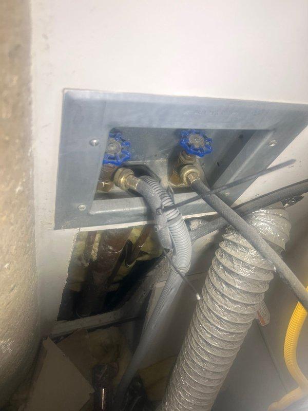 Responded to water leak service call for LG stacked washer/dryer unit. Inspected recessed utility box containing dual water supply valves with blue handles and flexible supply lines. Successfully diagnosed and repaired leak in washer supply connection, ensuring proper water flow and preventing further water damage.