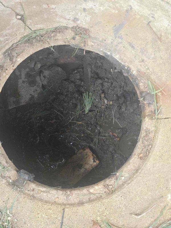 Inspected catch basin with standing water and sediment accumulation. Observed blocked drainage pipe with significant debris and mineral buildup. Customer advised that pump is currently frozen; scheduled return visit for next week to complete pump service after thaw.