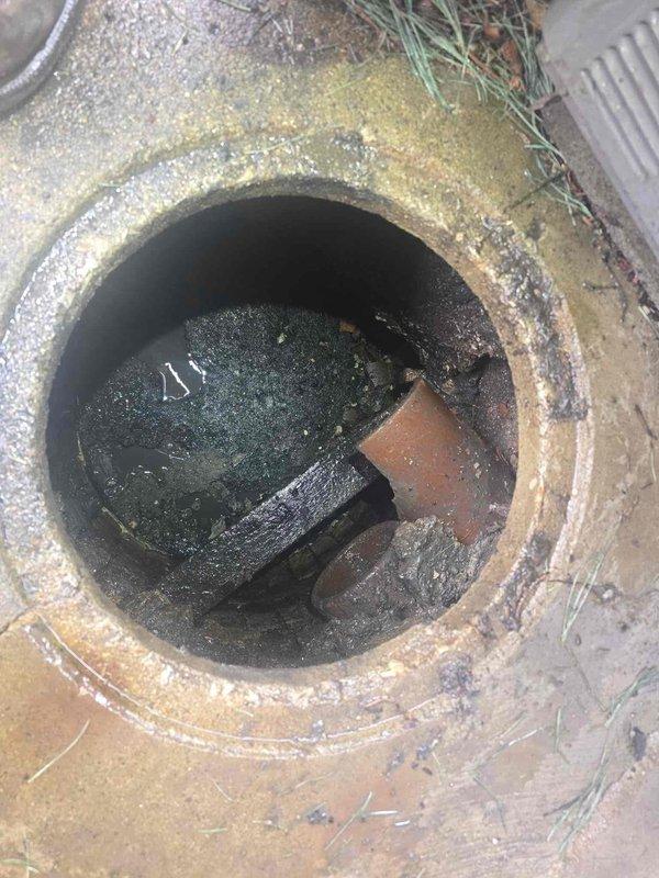 Inspected catch basin with standing water and sediment accumulation. Observed blocked drainage pipe with significant debris and mineral buildup. Customer advised that pump is currently frozen; scheduled return visit for next week to complete pump service after thaw.