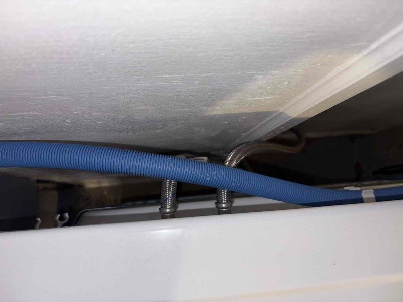 Performed assessment for potential water softener installation and hot water connection to washing machine. Inspected existing plumbing infrastructure, noting deteriorated pipe connections with visible corrosion and aging components. Documented current setup including flexible blue conduit and mounting fixtures to determine optimal integration points for requested water treatment system.