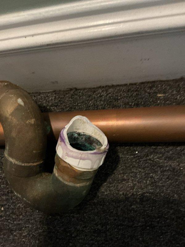 Opened ceiling beneath shower to inspect plumbing issues, revealing water damage to wooden joists and a corroded copper pipe with temporary tape repair. Identified leaking P-trap connection to the main drain line and evidence of previous moisture infiltration requiring replacement of affected plumbing components.