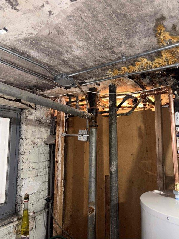 Conducted comprehensive assessment of severely water-damaged basement utility area with extensive ceiling deterioration, mold growth, and compromised wooden structural elements. Inspection revealed multiple copper and metal pipes requiring attention, with temporary support poles currently stabilizing the structure. Recommended complete plumbing system overhaul and remediation of water damage to prevent further structural compromise and mold proliferation.