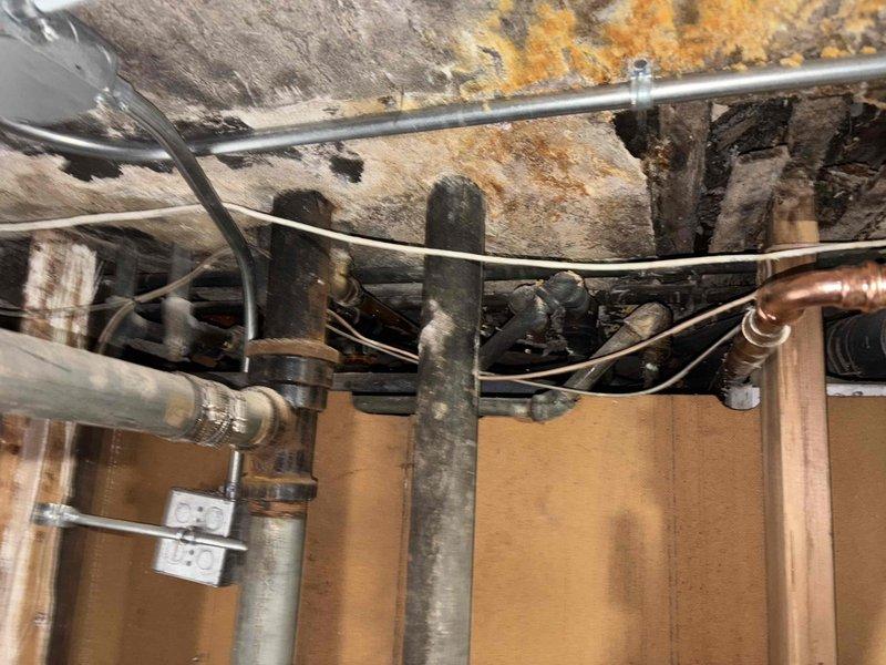 Conducted comprehensive assessment of severely water-damaged basement utility area with extensive ceiling deterioration, mold growth, and compromised wooden structural elements. Inspection revealed multiple copper and metal pipes requiring attention, with temporary support poles currently stabilizing the structure. Recommended complete plumbing system overhaul and remediation of water damage to prevent further structural compromise and mold proliferation.