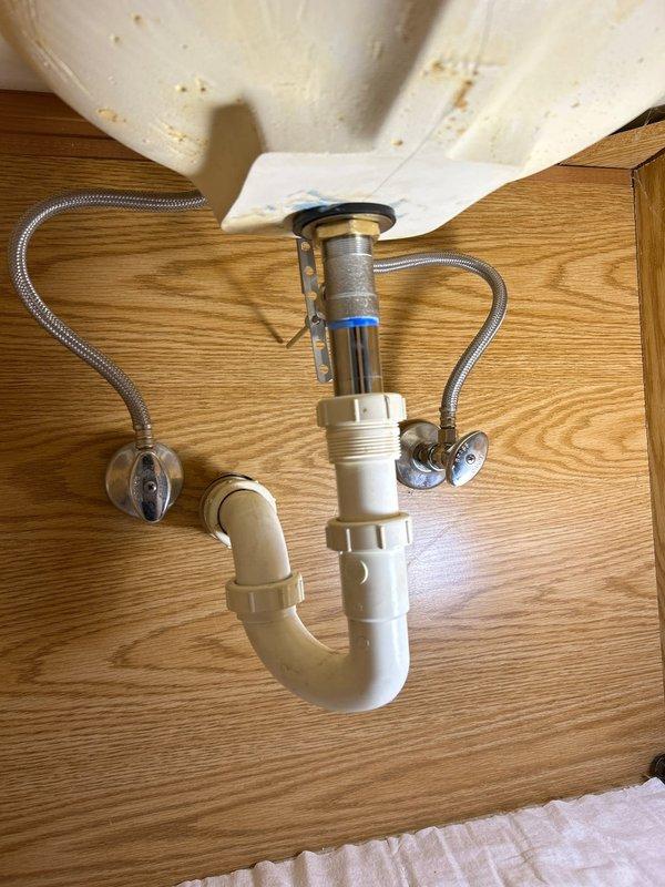 Responded to service call regarding toilet tank leaking from the back. Upon inspection, found the leak was actually originating from the bathroom sink plumbing. Examined the underside components, including PVC P-trap and supply lines with shut-off valves. Tightened loose connections and verified proper water flow and drainage. All plumbing now functioning correctly with no leaks present.
