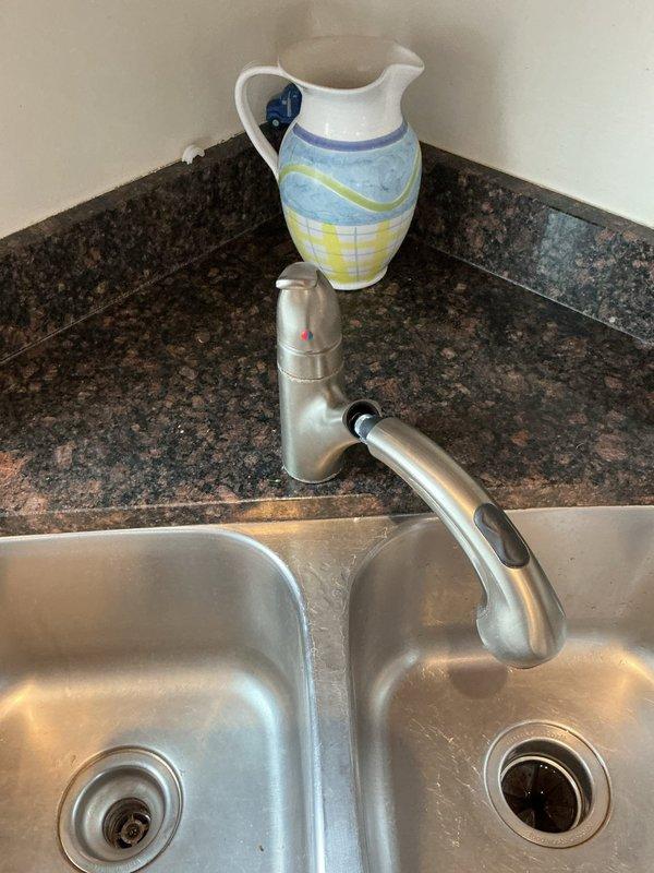 Replaced 15-year-old kitchen faucet with new single-handle model to resolve heavy dripping issue. Removal of old fixture and installation of new brushed nickel pull-out sprayer faucet was completed at double-basin stainless steel sink set in granite countertop. All connections were tested to ensure proper function with no leaks.