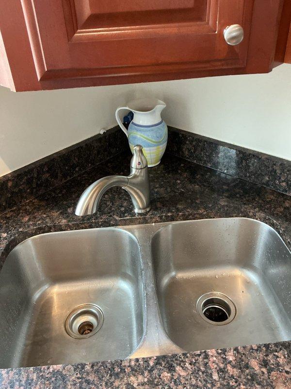 Replaced 15-year-old kitchen faucet with new single-handle model to resolve heavy dripping issue. Removal of old fixture and installation of new brushed nickel pull-out sprayer faucet was completed at double-basin stainless steel sink set in granite countertop. All connections were tested to ensure proper function with no leaks.