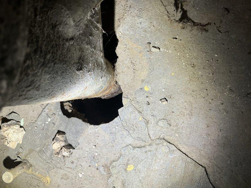 Inspected basement sewer system after customer reported sewer gas odors in basement and attic, particularly after rainfall. Identified an open drain connection without proper trapping in the basement that was allowing sewer gases to escape. Discovered significant structural deterioration in concrete surrounding the drain connection and documented a brick well structure with standing water that required remediation. Installed proper P-trap and sealed deteriorated concrete to eliminate gas escape paths.