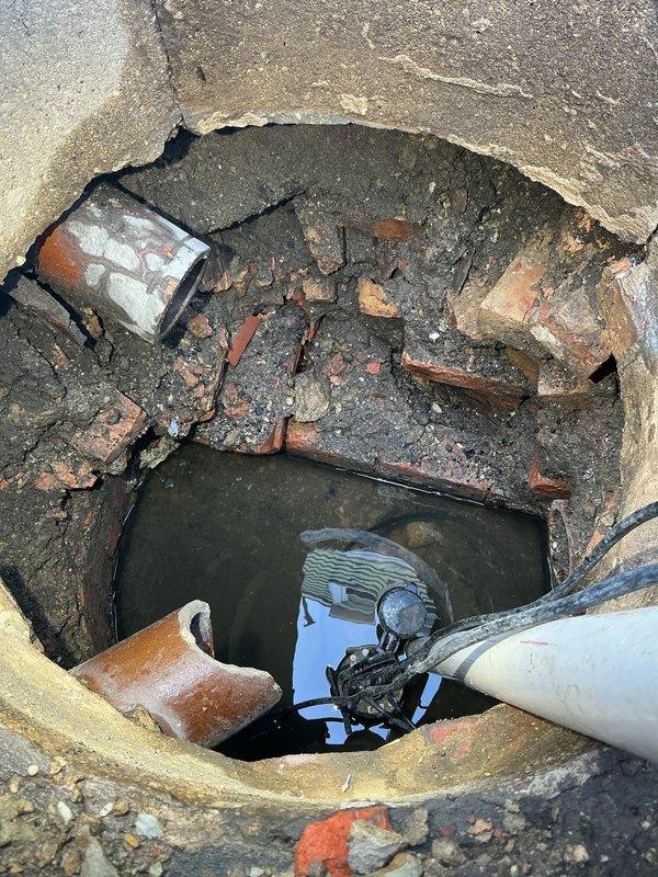 Conducted inspection of damaged catch basin in backyard using specialized camera equipment. Documented significant structural deterioration, including broken brickwork, damaged terracotta piping, and standing water accumulation. Provided estimate for complete catch basin rebuilding as requested.