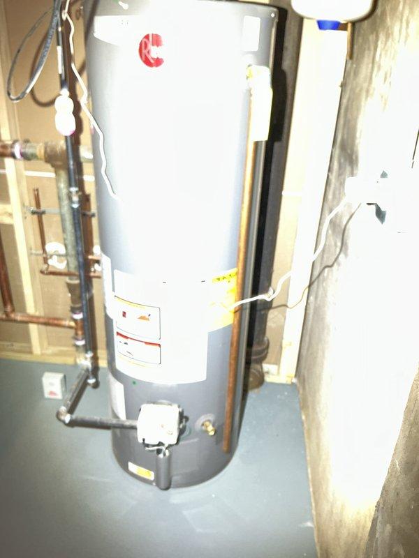 Responded to service call for water heater inspection. Examined unit and connections, confirming proper installation of the cylindrical water heater with copper pipe connections. Inspected exterior electrical components including weatherproof outlet box and utility connection on brick exterior wall.
