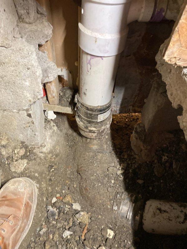 Completed underground pipe repair by replacing corroded metal fitting connected to PVC line. Installed new coupling with proper leveling to ensure horizontal alignment, addressing water flow issues in basement/crawlspace area.