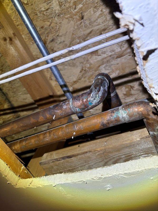 Located and repaired a pinhole leak in copper supply piping located above bedroom ceiling. Accessed plumbing through ceiling opening where significant oxidation and corrosion were observed on copper pipes. Replaced damaged section of pipe to resolve persistent slow leak.