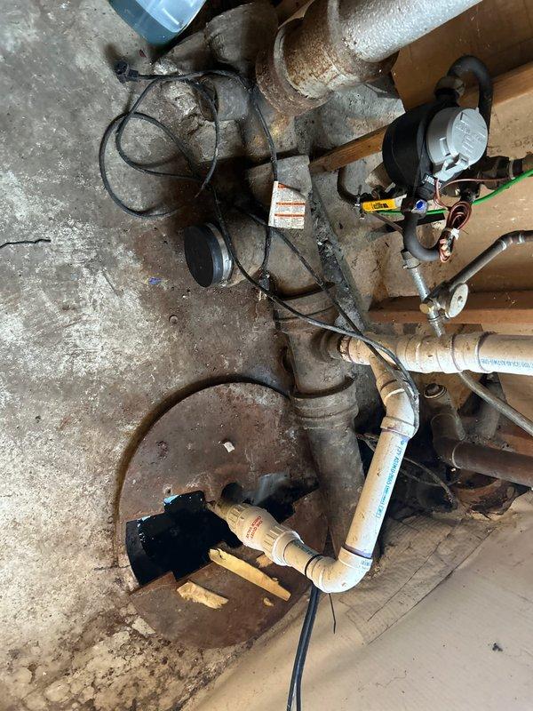 Inspected failed sump pump system in basement of century home, documenting extensive corrosion on metal pipes and drainage infrastructure. Determined pump (installed 2024) was still under warranty and initiated warranty claim process for replacement unit. Cleaned debris from drainage grate and advised homeowner on temporary water management solutions until replacement can be installed.