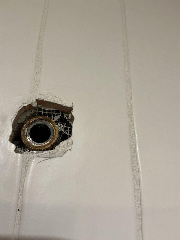 Repaired and remounted detached showerhead fixture in 56-year-old residence by reinforcing damaged wall substrate, installing new backing supports, and securing the brass pipe fitting. Removed deteriorated plaster and wire mesh, sealed exposed areas, and verified proper installation with leak testing to ensure fixture stability and prevent future detachment.