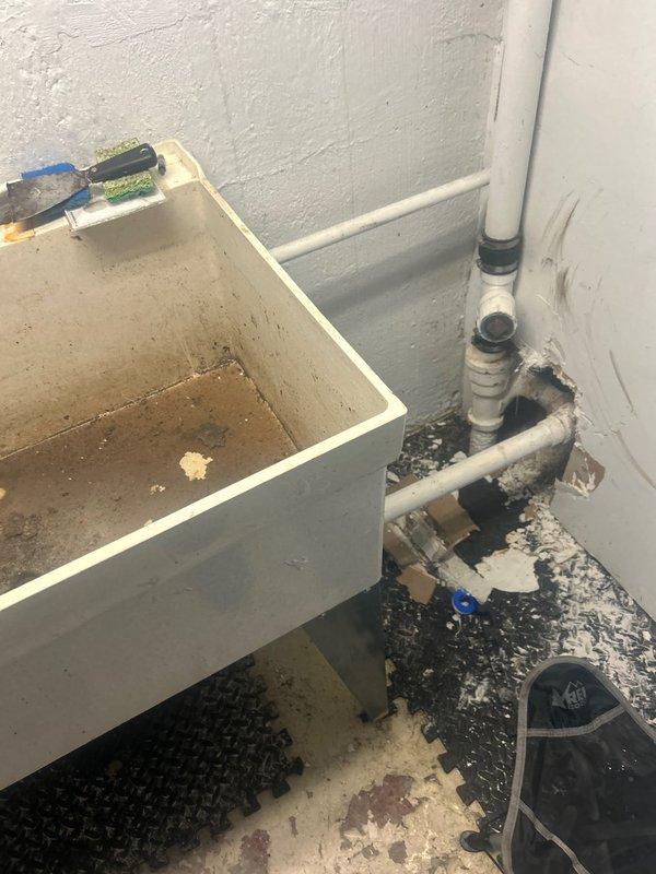Performed inspection of kitchen sink drainage system that shares stack with utility sink/laundry in basement. Identified access point at catch basin approximately 10 feet from house. Visual inspection revealed significant debris accumulation and deterioration at pipe connection to wall near utility sink, with evidence of previous water damage to surrounding floor area. Conducted hydro jetting service to clear blockage and restore proper drainage function throughout the system.