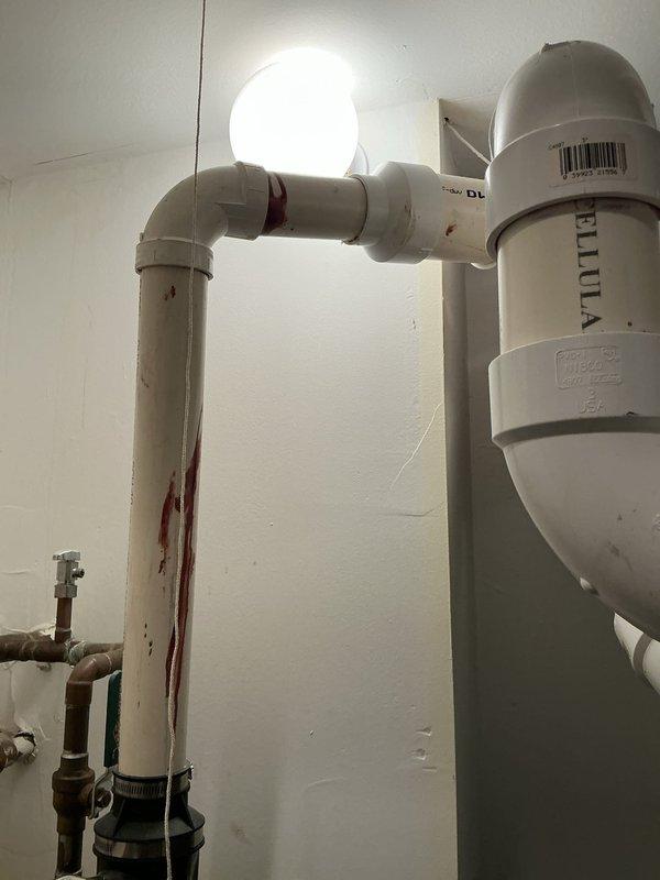 Responded to priority leak investigation in ceiling above hot water heater in mechanical closet. Inspected PVC drainage system suspected to be from unit above, identifying reddish-brown staining on horizontal pipe sections indicating the source of the leak. Documented the plumbing configuration including pump installation, copper supply lines, and PVC drainage components for comprehensive assessment.