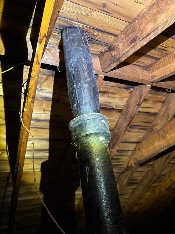 Inspected vent stack in attic where black pipe had blown out causing a leak through the hallway ceiling. Documented damaged pipe connection and surrounding conditions, including disturbed insulation around the plumbing system. Evaluation confirmed need for vent stack repair to resolve the active leak.