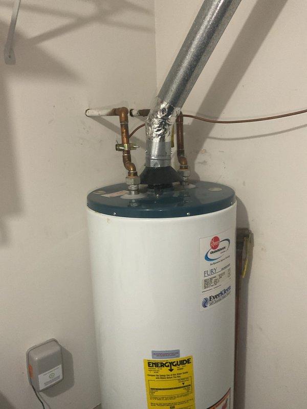 Inspected 40-gallon Fury water heater exhibiting active leakage from tank. Documented current installation configuration including copper supply lines, galvanized vent pipe, and existing valve connections. Recommended complete replacement of unit due to tank failure which cannot be repaired.