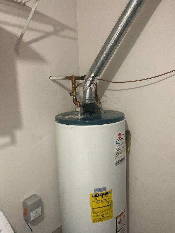 Inspected 40-gallon Fury water heater exhibiting active leakage from tank. Documented current installation configuration including copper supply lines, galvanized vent pipe, and existing valve connections. Recommended complete replacement of unit due to tank failure which cannot be repaired.