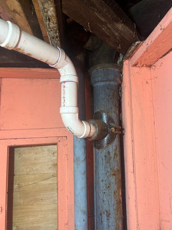 Conducted visual inspection of basement plumbing system where PVC piping connects to older metal drainage pipe via flanged fitting. Observed significant oxidation on the metal pipe section and documented potential leak point at the connection. Estimate prepared for replacement of deteriorated piping components to address active leak.