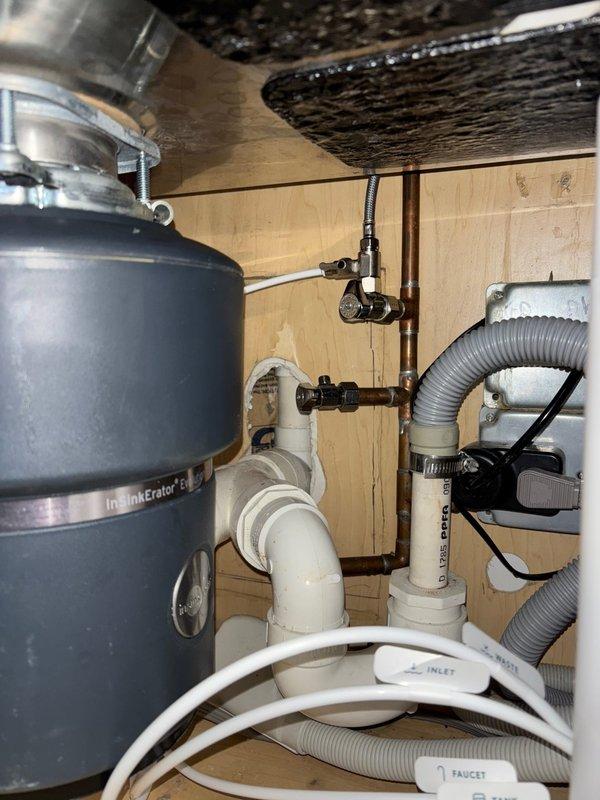Completed installation of InSinkErator garbage disposal unit with all necessary PVC connections, P-trap assembly, and proper water supply lines. Additionally, installed shower valve control fixture with diverter component on tiled wall, ensuring secure mounting and proper alignment for optimal water flow control.