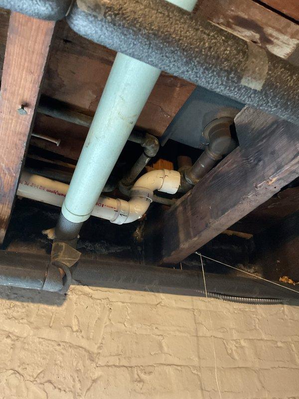 Cleared clogged bathroom tub drain by accessing the main drainage system in the crawl space. Inspected and serviced the PVC waste water lines, including the main vertical drain pipe and associated elbow joints, which revealed significant buildup causing the blockage that had resisted consumer-grade drain cleaners and manual rodding attempts.