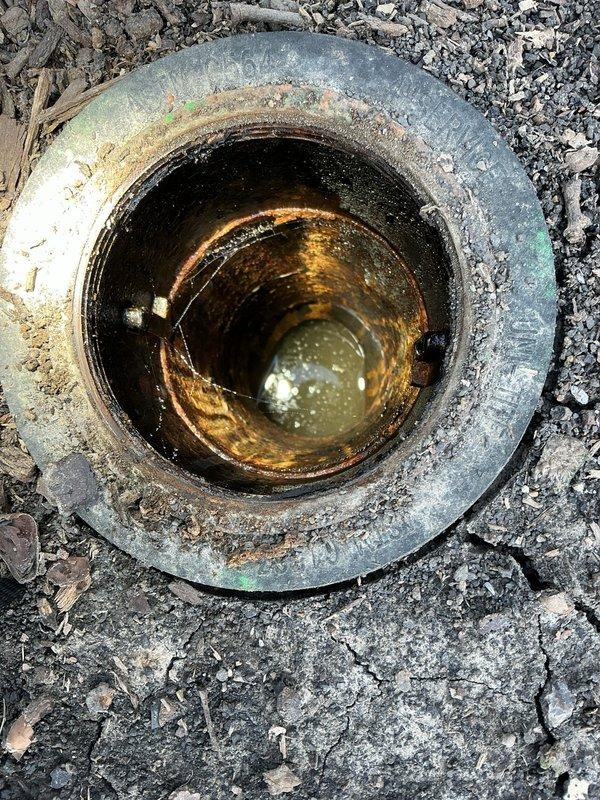 Responded to customer concern regarding excess water in backyard during rainfall. Inspected flood control system including manhole access point containing standing murky water and a circular drain pipe showing significant interior rust and water accumulation. Evaluation focused on drainage effectiveness and potential maintenance needs of both the flood control system and French drain.