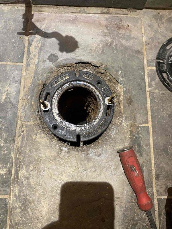 Removed and replaced deteriorated cast iron closet flange with new PVC closet flange securely installed within existing hub using lead pour method. Reinstalled customer's existing toilet with new wax ring and mounting bolts, ensuring proper seal and stable fixture mounting.