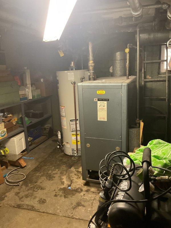 Responded to no hot water complaint from customer with 20-year-old 50-gallon water heater that ceased functioning two days prior. Upon inspection of the utility basement, observed the aging water heater adjacent to the furnace unit with visible signs of deterioration. Recommended replacement of the obsolete unit due to age and complete failure.