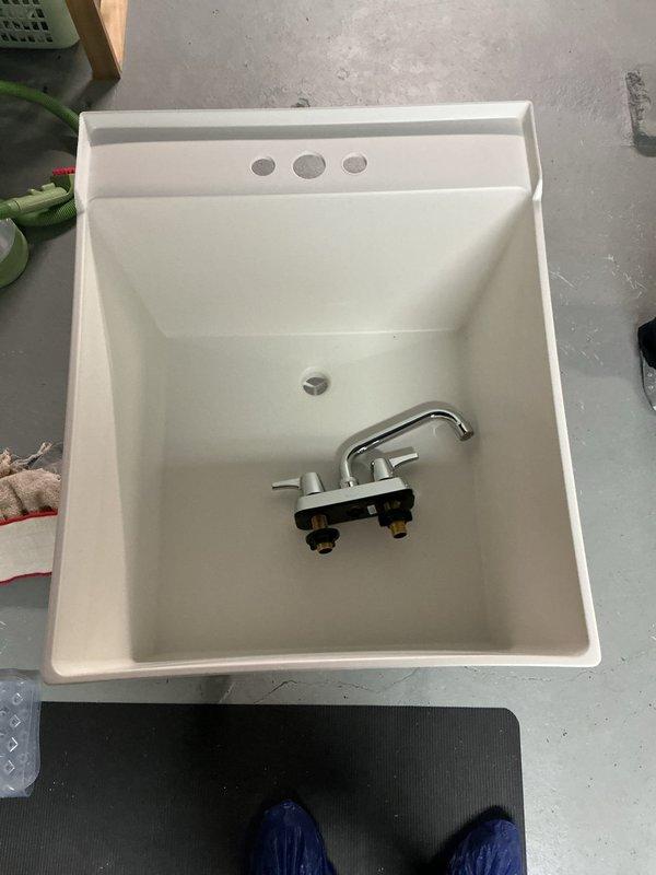 Conducted inspection of utility sink installation and assessed deteriorated drainage pipe. Installed new utility sink with standard two-handle chrome fixture. Documented extensive pipe degradation showing multiple cracks, fragmentation, and sediment buildup. Recommended options for addressing intermittent burping noise in kitchen sink that occurs after heavy rainfall when sump pump operates frequently.