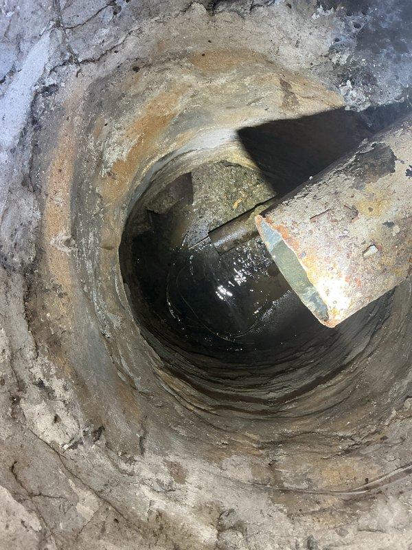 Responded to service call regarding a catch basin backup and sinkhole formation. Upon inspection, found a deteriorated catch basin with cracked walls, significant mineral buildup, and standing water containing concrete debris. Documented condition of the mechanical room infrastructure and drainage system for further assessment.