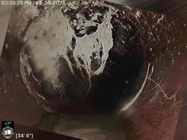 Conducted inspection of residential sewer line using camera system, identifying significant pipe deterioration at approximately 34'6" and 48'5" depths. Observed substantial mineral deposits, structural damage including visible cracks, and potential blockage in what appears to be clay/terracotta piping, recommending drain tile and sump pump installation to address these issues.
