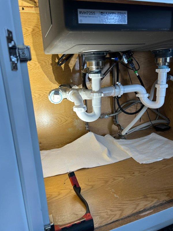 Completed drain assembly service on double-basin kitchen sink with RVH725S model fixture. Inspected and repaired P-trap configuration, ensuring proper connections between PVC components and metal drain flanges. Verified no leaks in plumbing system after service completion.