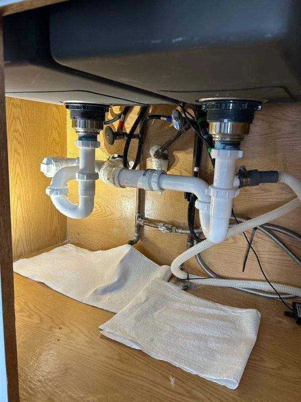 Completed drain assembly service on double-basin kitchen sink with RVH725S model fixture. Inspected and repaired P-trap configuration, ensuring proper connections between PVC components and metal drain flanges. Verified no leaks in plumbing system after service completion.
