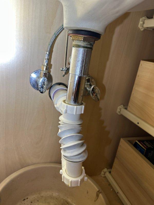Replaced deteriorated flexible accordion drain pipe and worn p-trap assembly under bathroom sink which was causing significant leakage. Installed new chrome p-trap with proper fittings and ensured all connections were secure and leak-free.