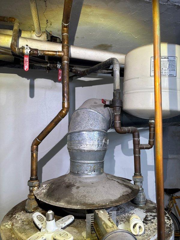 # Water Heater Replacement - Commercial Building

Responded to emergency service call for failed water heater in 6-unit commercial building. Upon arrival, assessed existing A.O. Smith water heater that had burst, causing immediate need for replacement to restore hot water service to all units. Documented existing installation including copper supply and distribution piping, expansion tank configuration, and gas line connections. Evaluated utility room conditions including overhead plumbing infrastructure, existing pipe corrosion, and available workspace for equipment replacement. Prepared comprehensive estimate for complete water heater replacement including removal of failed unit, installation of new appropriately-sized commercial water heater, reconnection of all water supply lines, gas line connections, expansion tank evaluation and replacement if necessary, and restoration of hot water service to building. Estimate includes all necessary materials, permits, and code-compliant insta