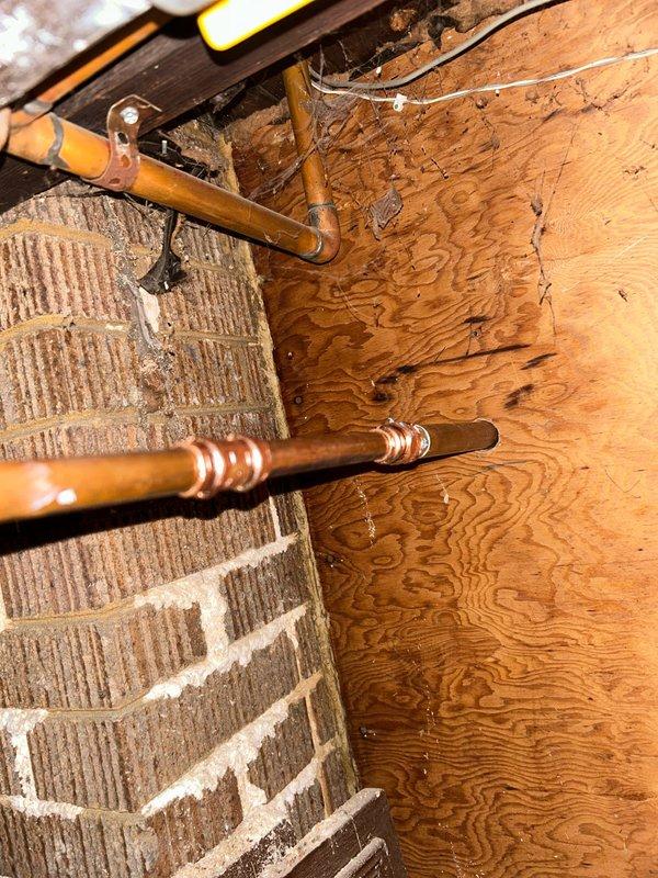 # Plumbing Service - Sold Repair Summary

Completed installation of new copper water supply lines in basement/crawl space area with connection to exterior hose bibb. Ran copper piping from interior plumbing system through foundation wall, properly securing lines along exposed brick and floor joists. Installed chrome-finished outdoor spigot with cross-handle shutoff valve on exterior white vinyl siding, ensuring proper mounting and weatherproof seal at wall penetration. All connections tested and verified leak-free with full water pressure.