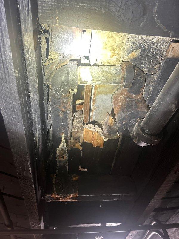 # Plumbing Estimate - DWV System Replacement

Conducted comprehensive assessment of deteriorated cast iron drain-waste-vent (DWV) system serving bathroom fixtures including tub and lavatory. Inspection revealed severely corroded cast iron branch piping with active leak at drum trap assembly. Documented extensive rust damage to horizontal waste lines and significant water damage to surrounding wooden framing members and joists, indicating prolonged moisture infiltration. 

Recommended complete removal of obsolete drum trap and replacement of compromised cast iron branch waste and vent lines with PVC piping system, properly tied into existing main stack. Scope includes opening interior wall cavity for access to affected plumbing, removal of all deteriorated piping, installation of code-compliant PVC drainage system with proper venting, and assessment of water-damaged structural framing for potential repair or reinforcement requirements.