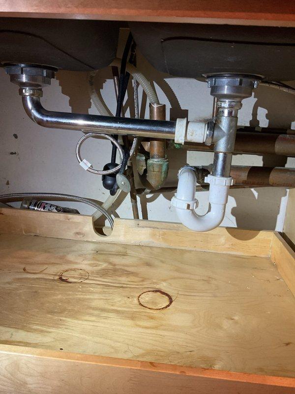 # Job Description

Responded to service call for completely non-draining double-basin kitchen sink with stainless steel fixtures and PVC drainage system. Upon arrival, found left basin heavily soiled with accumulated organic debris, grease buildup, and standing water, while right basin showed scattered residue and drainage blockage. 

Accessed plumbing assembly from cabinet below, which consisted of dual chrome drain baskets with metal tailpieces, white PVC P-traps, and standard double-basin drainage configuration. Disassembled P-trap connections to locate obstruction point. Removed significant accumulation of food waste, grease, and organic matter causing complete blockage in main drain line. Cleared both drain baskets and tailpieces of residual debris.

Inspected all PVC connections, fittings, and trap assembly for proper alignment and seal integrity. Reassembled drainage system with proper trap configuration to ensure adequate water seal. Tested both basins for proper drainage flow 