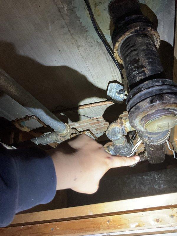 # Service Report

Responded to commercial property for water intrusion in basement originating from kitchen sink drain system. Upon investigation, accessed crawl space and identified failed drainage piping with severe corrosion and deterioration causing water to leak from plumbing assembly rather than flowing through drain line properly. Inspected affected plumbing infrastructure including drain stack connections and horizontal waste lines. Found compromised pipe integrity with extensive rust buildup and structural degradation requiring immediate attention. Documented existing conditions showing advanced corrosion on metallic components and aging pipe connections. Cleared immediate blockage and assessed full extent of drainage system failure to provide recommendations for necessary repairs to restore proper function and prevent continued water damage to basement area.