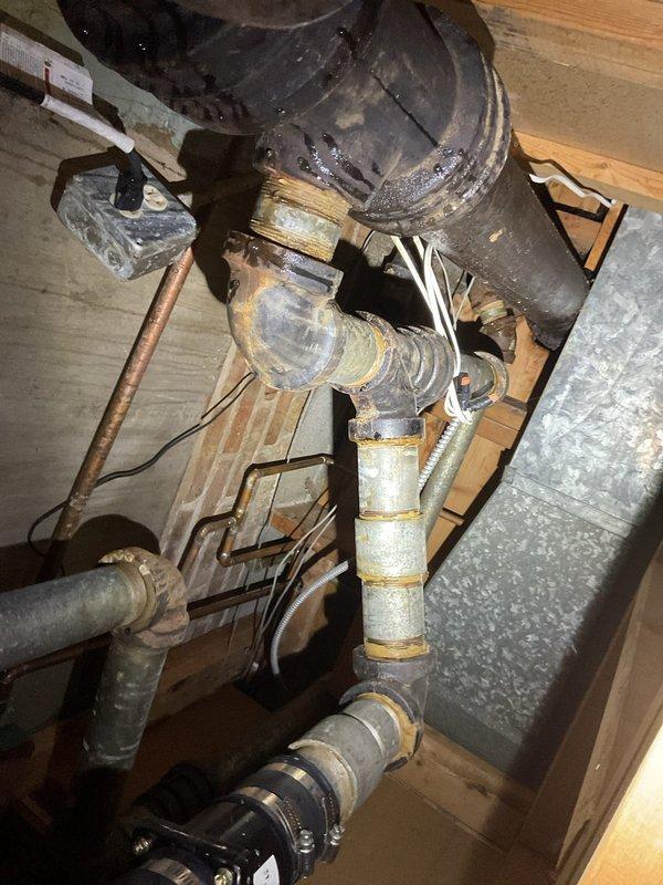 # Service Report

Responded to commercial property for water intrusion in basement originating from kitchen sink drain system. Upon investigation, accessed crawl space and identified failed drainage piping with severe corrosion and deterioration causing water to leak from plumbing assembly rather than flowing through drain line properly. Inspected affected plumbing infrastructure including drain stack connections and horizontal waste lines. Found compromised pipe integrity with extensive rust buildup and structural degradation requiring immediate attention. Documented existing conditions showing advanced corrosion on metallic components and aging pipe connections. Cleared immediate blockage and assessed full extent of drainage system failure to provide recommendations for necessary repairs to restore proper function and prevent continued water damage to basement area.