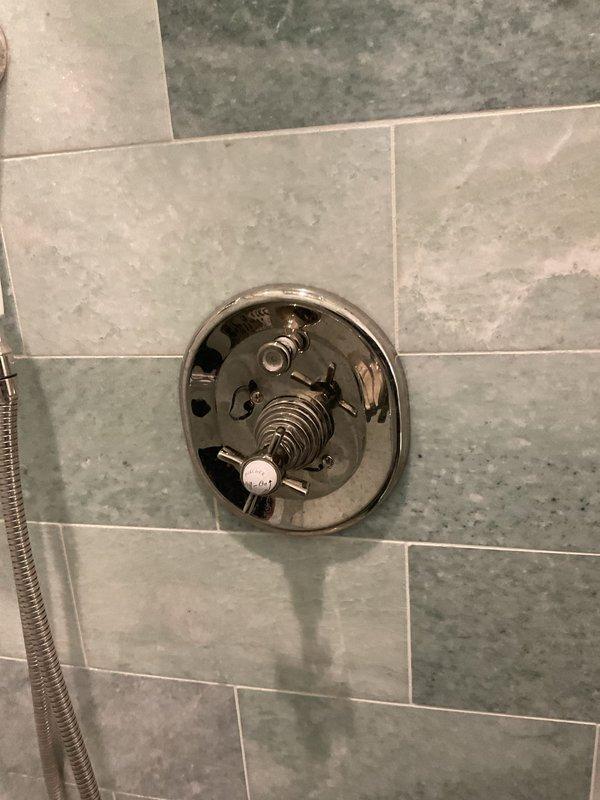 # Plumbing Service Report - Shower/Tub

Responded to callback for difficult-to-operate shower valve with internal noise following previous service visit. Upon inspection, found shower valve cartridge improperly seated within valve body, causing binding during operation and audible grinding when handle was turned. Disassembled valve trim and extracted cartridge to examine internal components. Identified debris and mineral buildup within valve body from century-old plumbing system, which prevented proper cartridge alignment during prior installation. Thoroughly cleaned valve body cavity, removed sediment accumulation, and verified proper fitment of replacement cartridge. Reinstalled cartridge with correct orientation, ensuring smooth operation throughout full range of motion. Tested hot and cold water flow, confirmed proper temperature control, and verified elimination of internal noise. Valve now operates smoothly with no binding or audible issues.