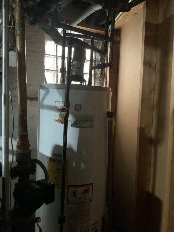 # Tanked Water Heater Service Report

Responded to service call for leaking residential hot water heater in basement utility area. Upon arrival, performed visual inspection of GE-branded tank water heater and surrounding plumbing connections. Identified active leak source and assessed water heater condition, age, and operational status. Examined inlet and outlet connections, temperature and pressure relief valve, drain valve, and gas supply line for signs of failure or deterioration. Documented equipment condition and leak location through photographic evidence showing water heater installation, associated piping, and mechanical system layout. Provided customer with diagnostic findings and recommended repair or replacement options based on severity of leak and overall unit condition.
