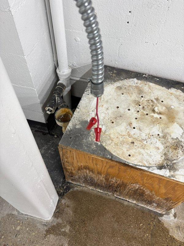 # Plumbing Service Report

Responded to a morning service call for plumbing repair assessment. Upon inspection, identified water damage and deterioration at the base of existing plumbing installation, evidenced by significant staining on wooden platform and surrounding concrete floor, indicating previous or ongoing moisture intrusion from plumbing connections. Documented existing copper piping system and associated fixtures, including brass valve connections and PVC drainage components in utility area. Provided customer with repair recommendations to address water damage concerns and ensure proper system operation.