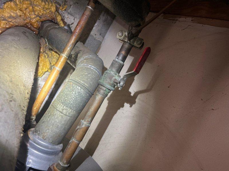 Provided estimate for relocating laundry and dryer hookup away from electrical panel to area near existing water supply lines. Assessed current plumbing configuration including water heater connections, copper supply lines showing corrosion, shut-off valve assembly, and insulated piping to determine optimal routing for relocated washer box installation.